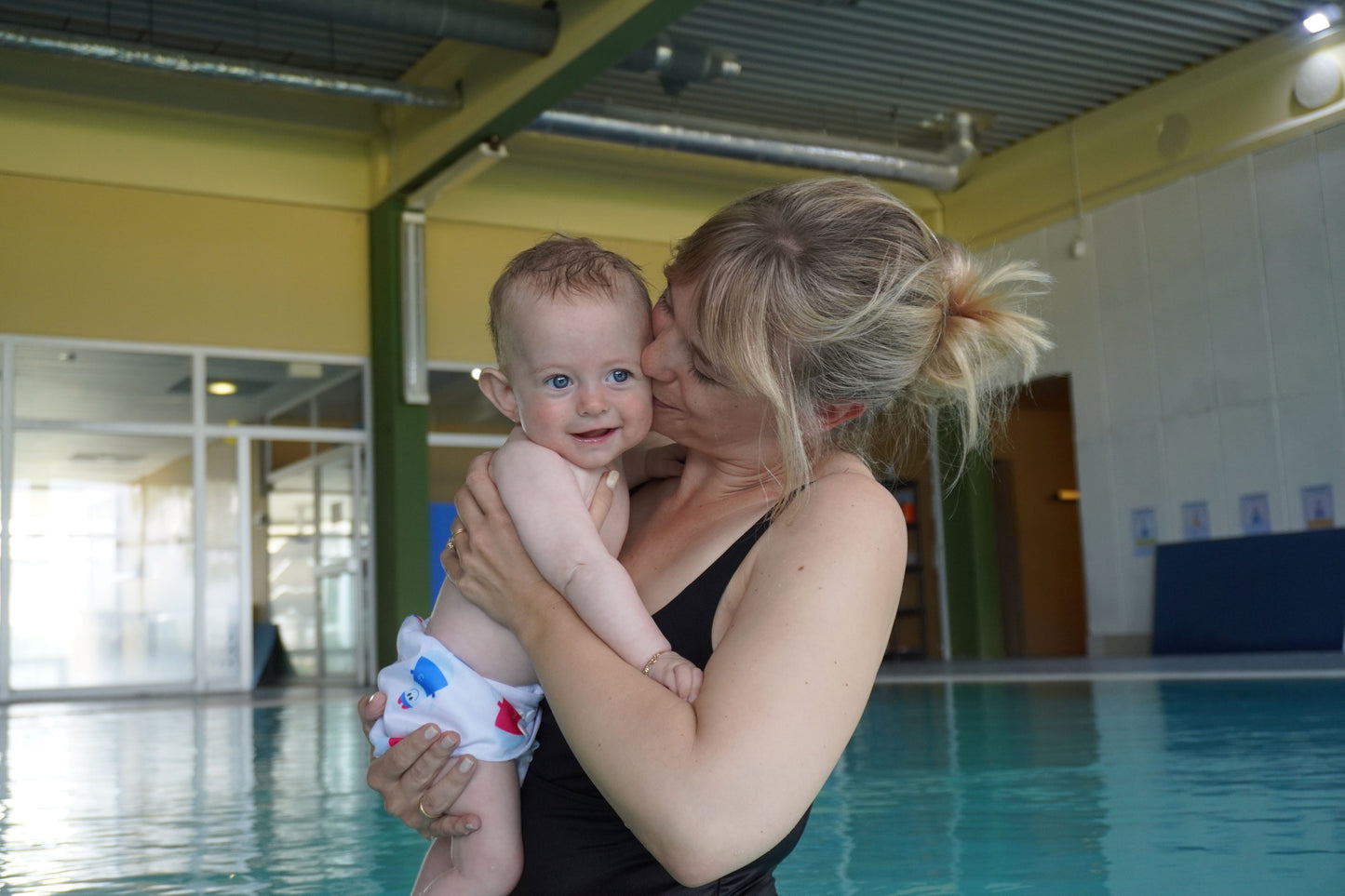 Mutter mit Baby auf dem Arm, Mutter küsst dem Baby auf die Wange, Baby lacht