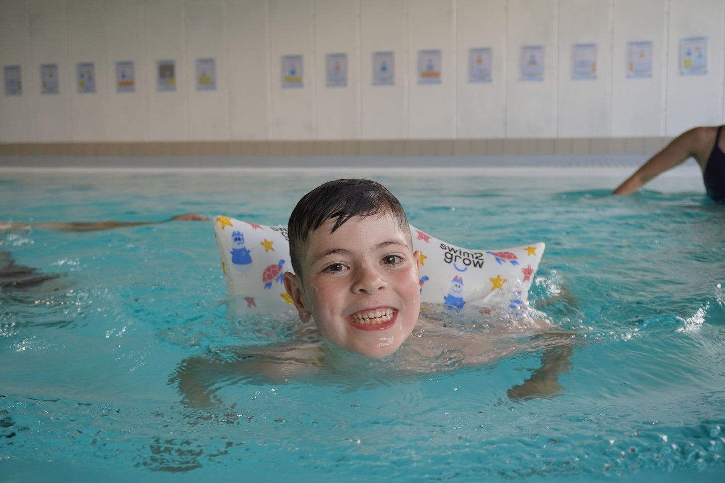 Grinsender Junge im Pool mit Schwimmkissen